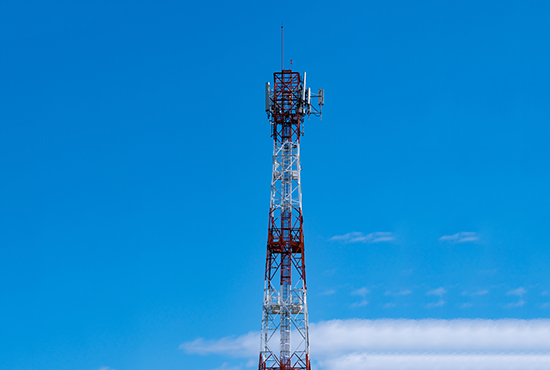 Telecommunication tower with blue sky and white clouds background. Antenna on blue sky. Radio and satellite pole. Communication technology. Telecommunication industry. Mobile or telecom 4g network.